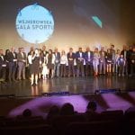 Kilkudziesięciu wyróżnionych sportowców stoi w szeregu na scenie pod baneremem „Wejherowska Gala Sportu”, widok od strony widowni